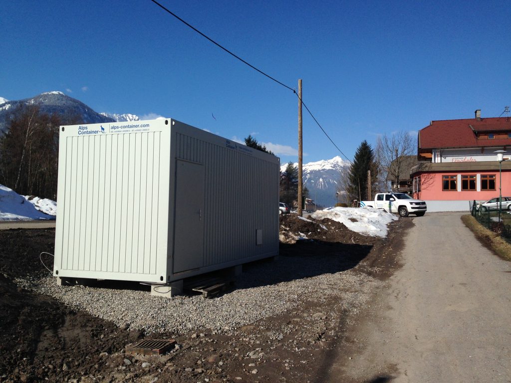 Baucontainer mit PickUp im Hintergrund